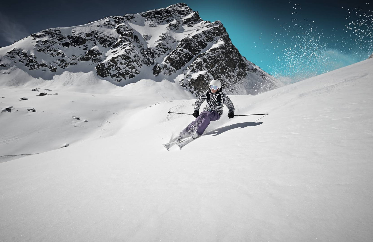 Woman speeding down a ski slope while keeping good form, an important step toward avoiding a ski injury