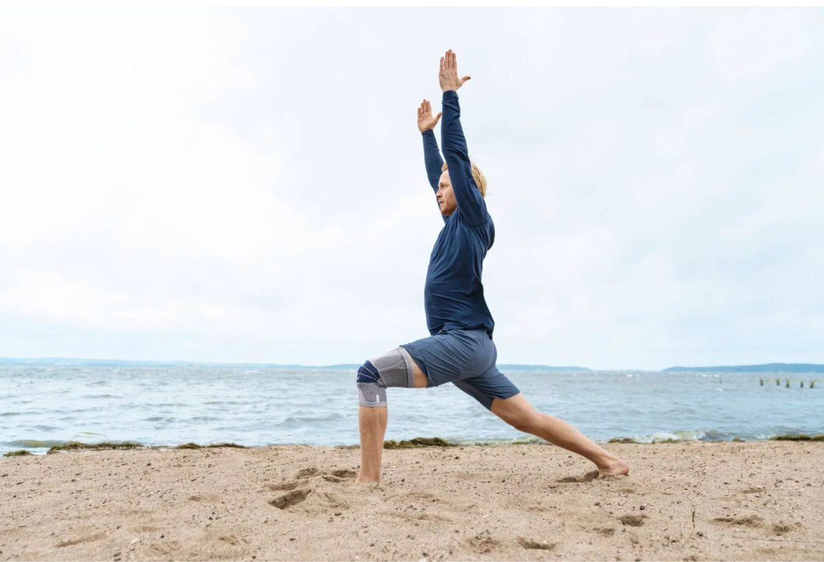 Man at the beach. He is doing lunges in Bauerfeind's GenuTrain Knee Brace, a good way to relieve knee pain