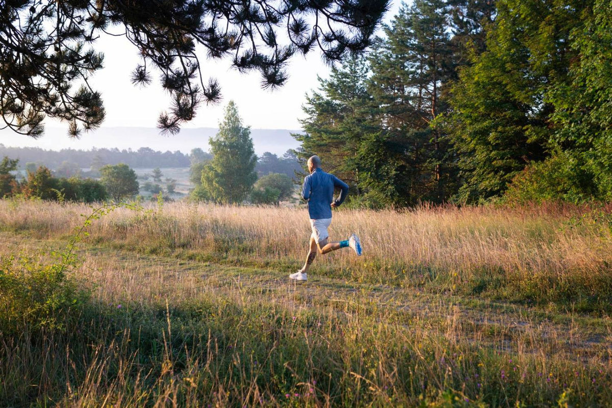 Man running through the park wearing the Bauerfeind Sports Achilles Support to help with Achilles pain when running