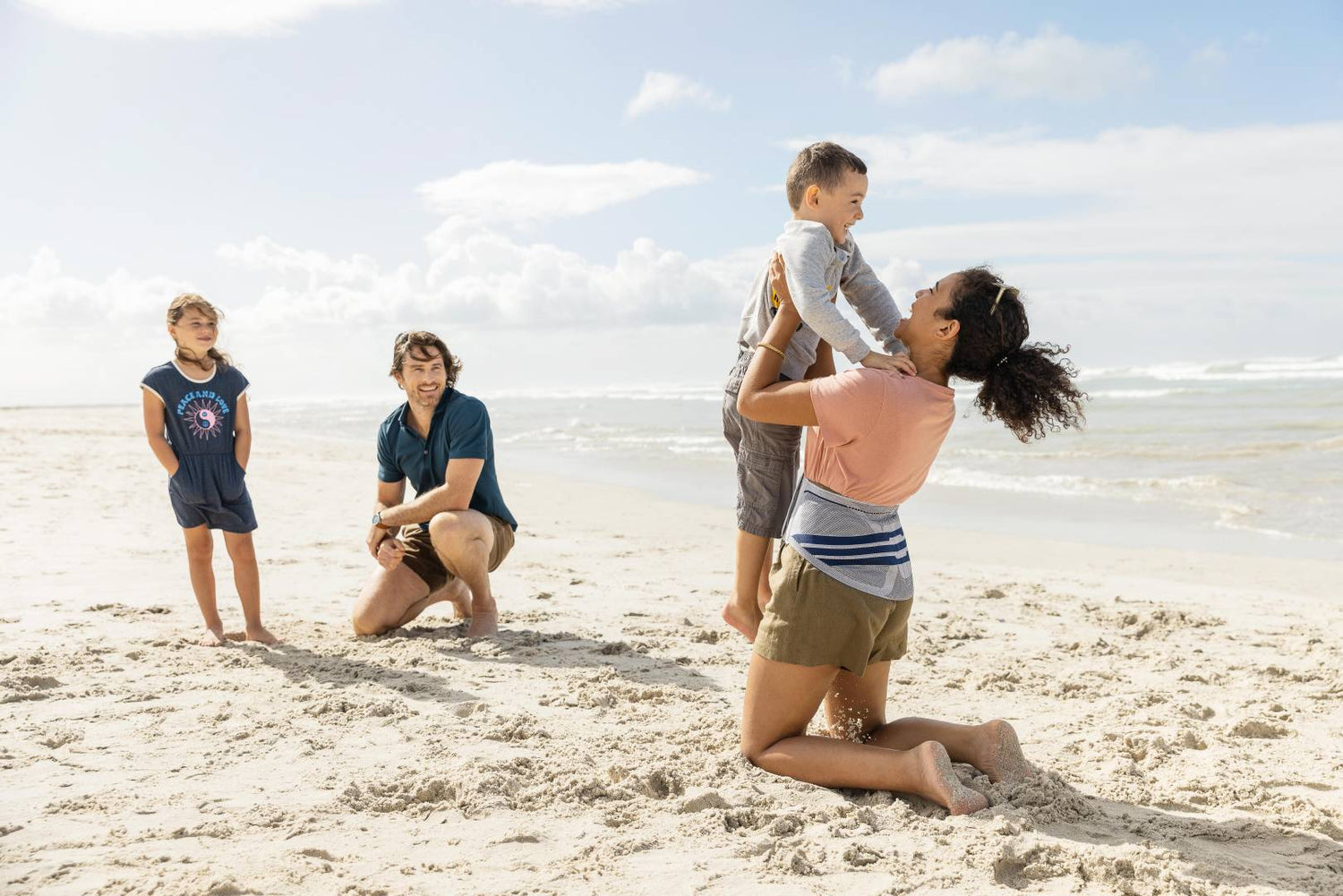 Woman wearing Bauerfeind's back brace to relieve back pain while at the beach with her family