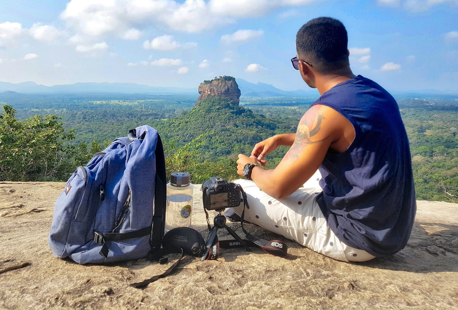 Man sitting at the top of a mountain, resting his knees after walking too much