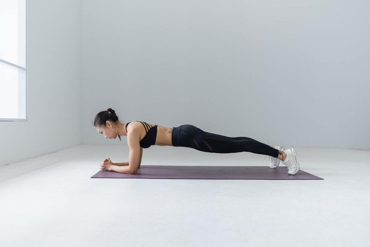 Woman doing a plank on a yoga mat. Photo by Li Sun from Pexels
