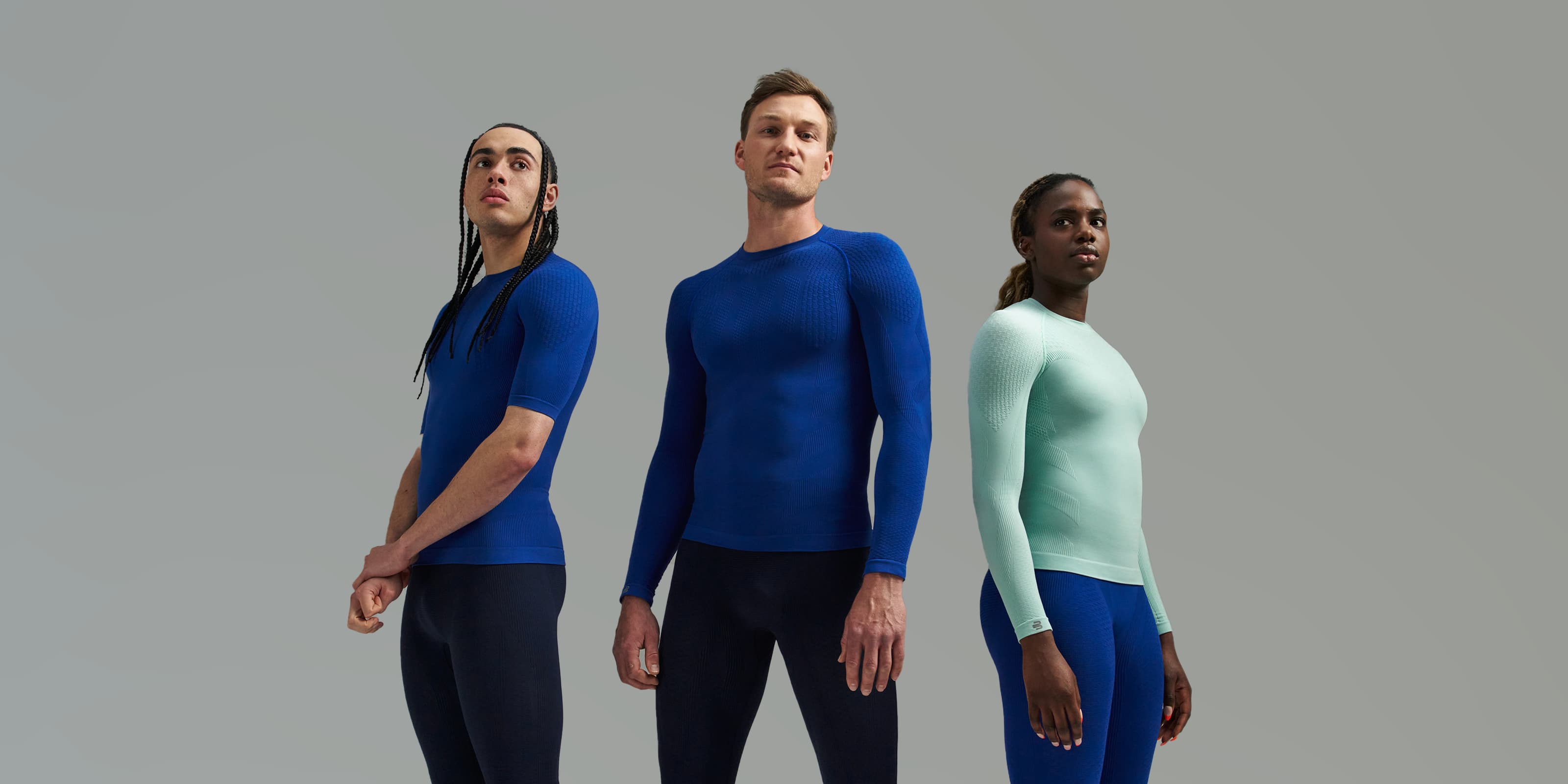 Three models wearing Bauerfeind Compression Wear in blue and turquoise on a grey background.
