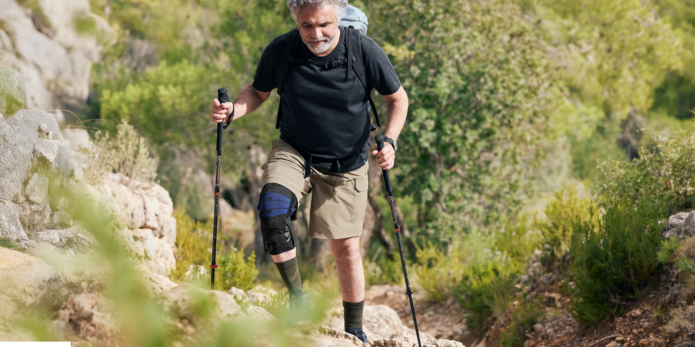 A man hiking wear a Bauerfeind GenuTrain OA Knee Brace