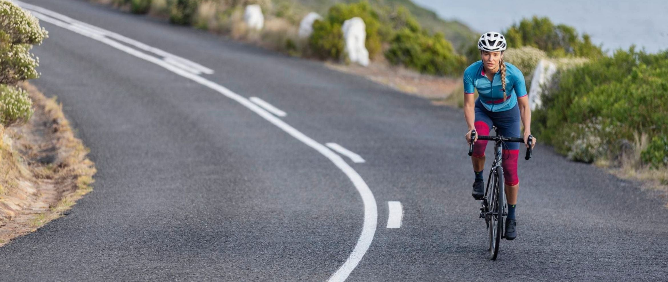 woman cycling along a road. She is wearing Bauerfeind's Sports Compression Knee Braces