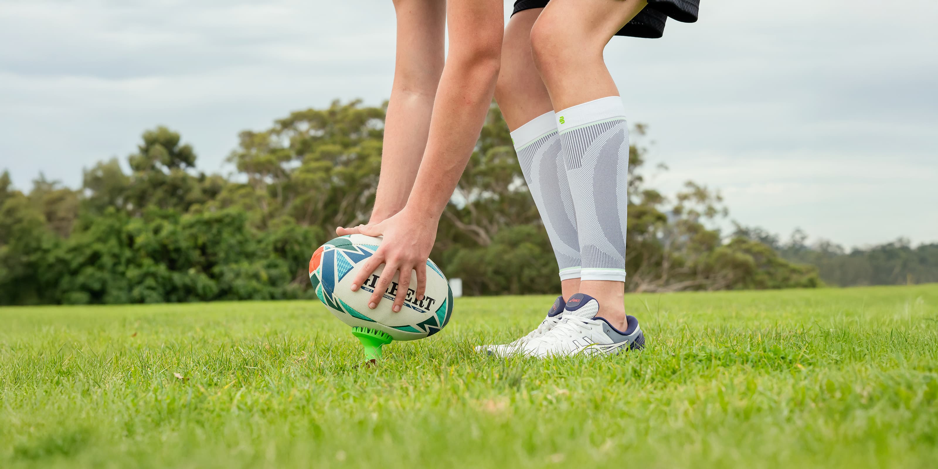 A male holding a rugby ball wearing Bauerfeind Compression Calf Sleeves