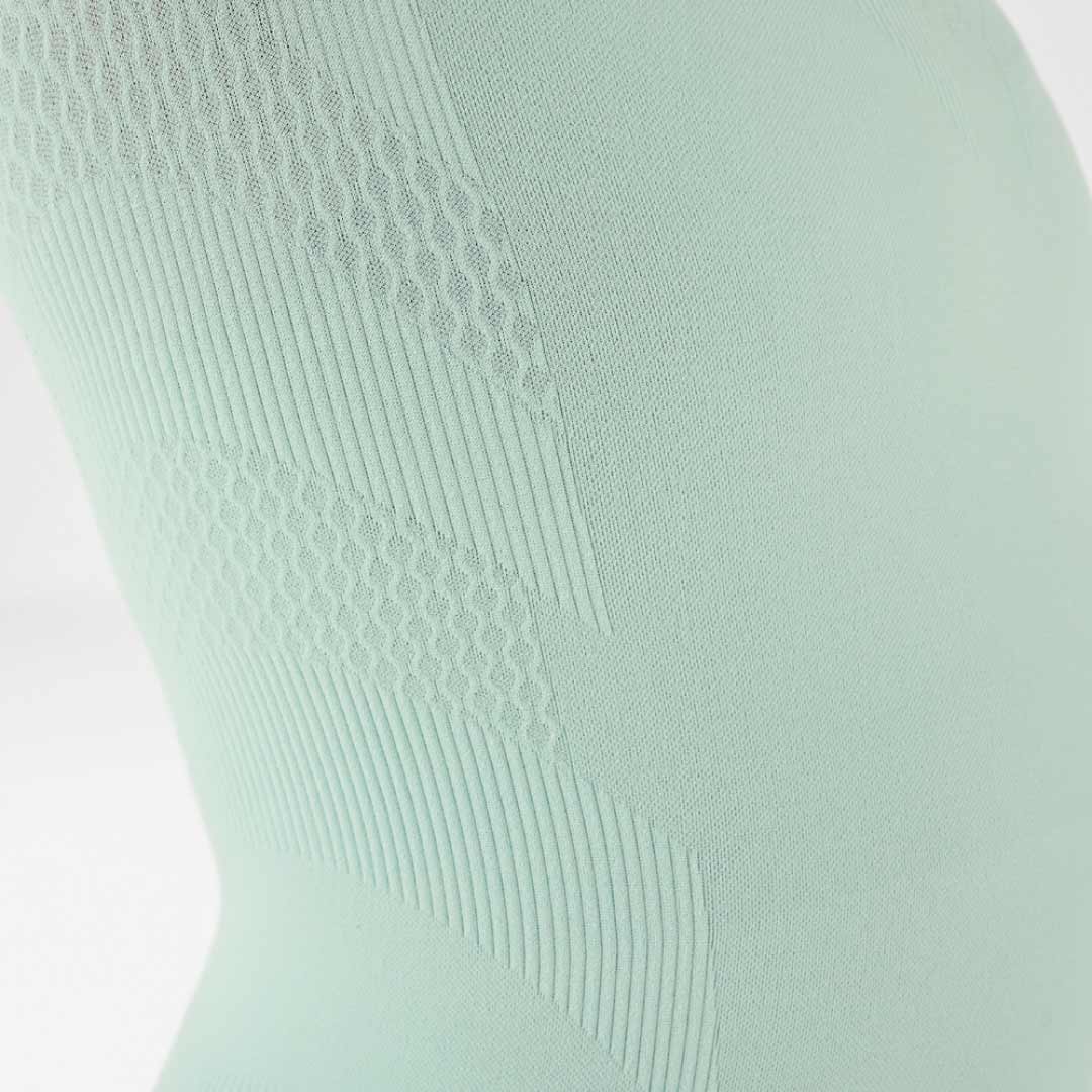 Close-up of a light green Bauerfeind compression shirt with textured pattern on a white background