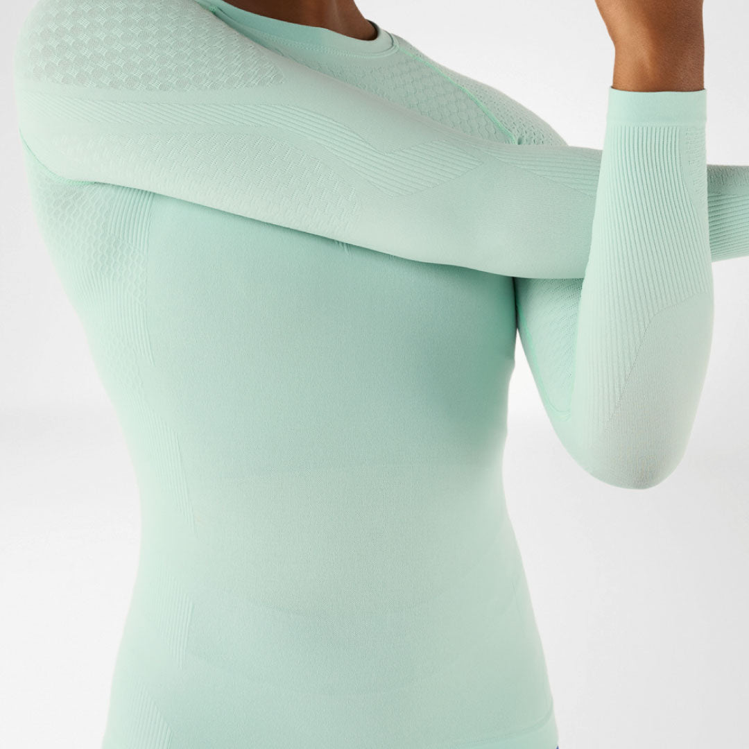 Light green Bauerfeind compression shirt worn by a person on a white background