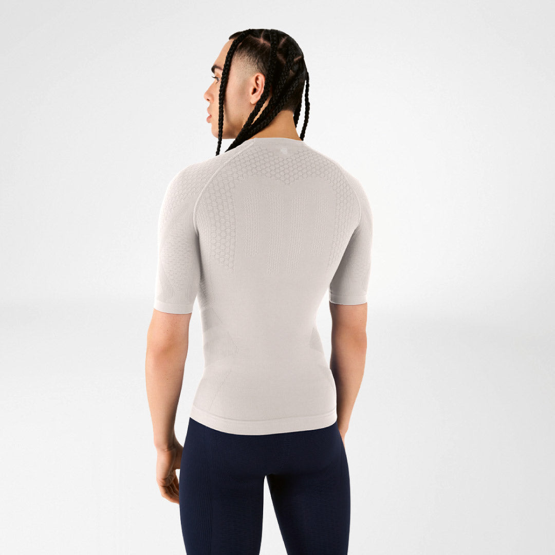 Person wearing a fitted silver-grey Bauerfeind compression shirt and dark leggings on a white background.