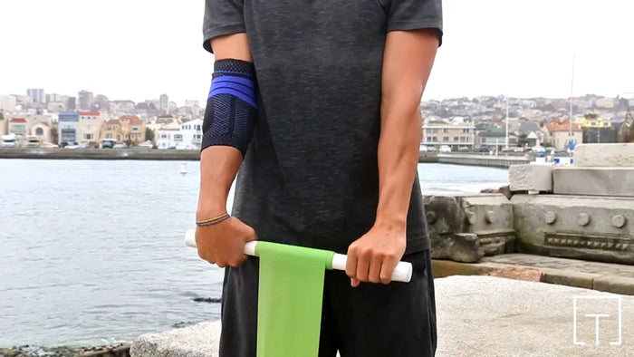 Man performing the wrist roller extensions workout at the harbour. He's wearing the EpiTrain Elbow Brace for pain relief and stabilily