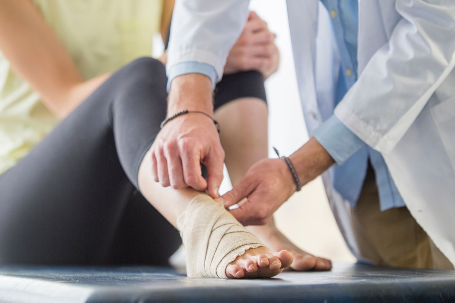 woman at the physiotherapist getting her swollen ankle wrapped in a compression bandage