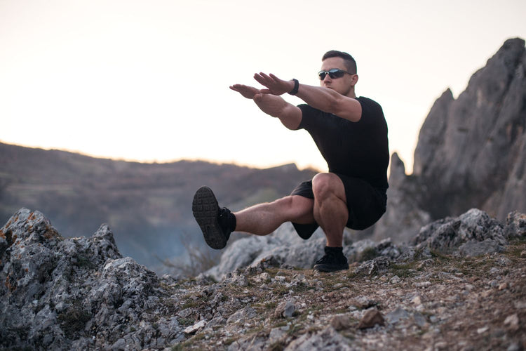 Man doing single leg squats on a mountain