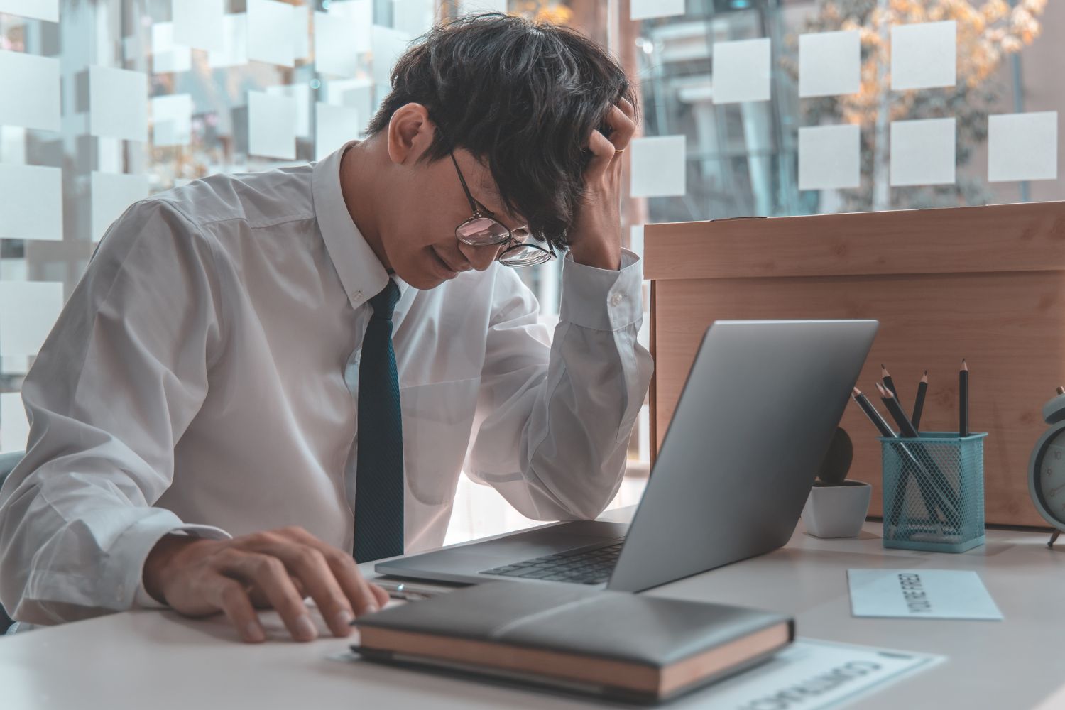 man sitting with poor posture, slouched over his laptop at his desk