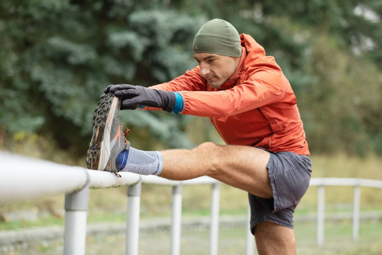 man stretching at a running track. He is wearing the AchilloTrain Ankle Support for Achilles Pain Relief