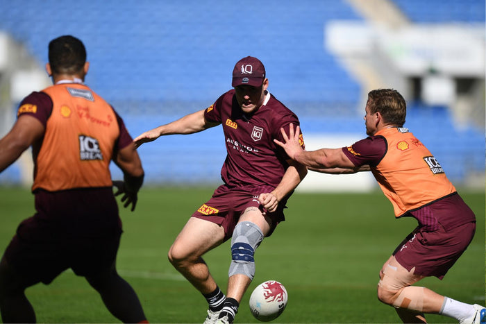 Three Rugby players playing a training match. The one in the middle is wearing Bauerfeind's GenuTrain Knee Support to maximise training efficiency and reduce risk of injury