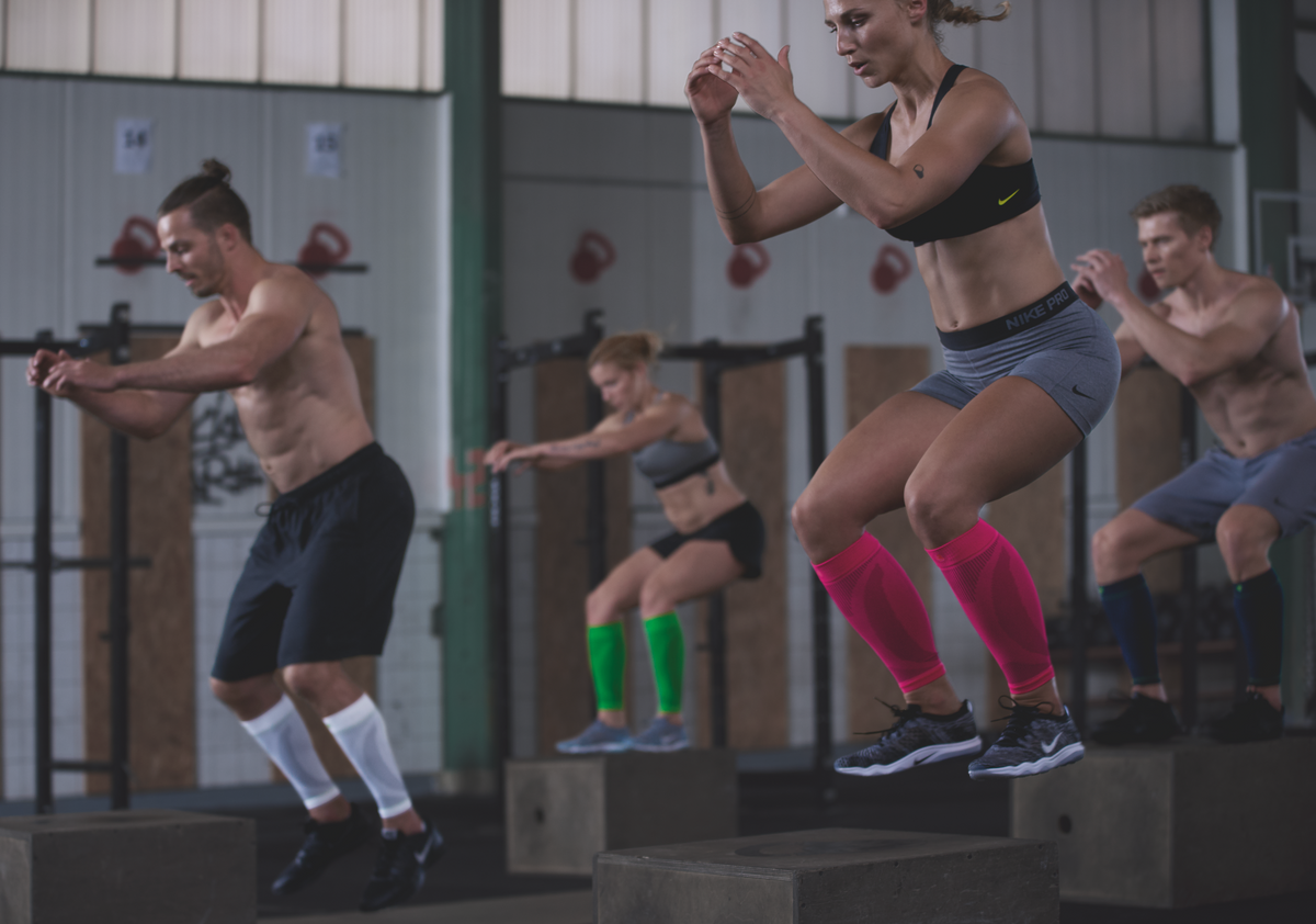 People doing box jumps as part of a cross fit class. They're wearing Calf Compression Sleeves