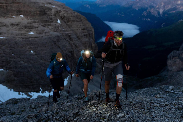 People hiking in the dark in the snowy mountains. They are wearing Bauerfeind Compression Supports