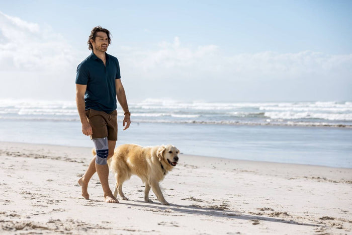 man walking on the beach with his dog for his health
