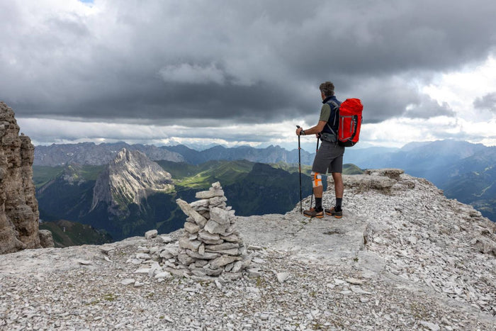 man hiking through the mountains looking at the view. He is wearing Bauerfeind's Outdoor Knee Support