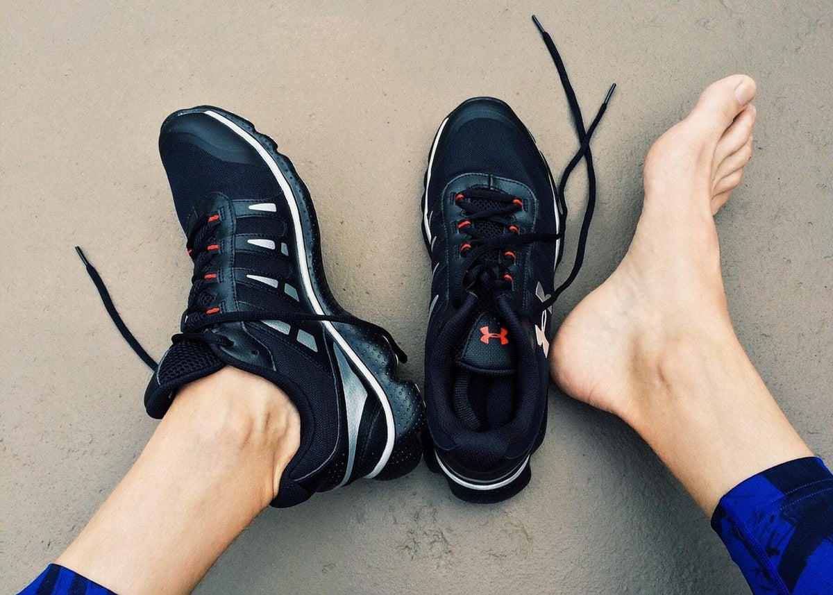Woman wearing one sports running shoe with one shoe barefoot. Image is linked to ankle injury article. Credit: Pexels.