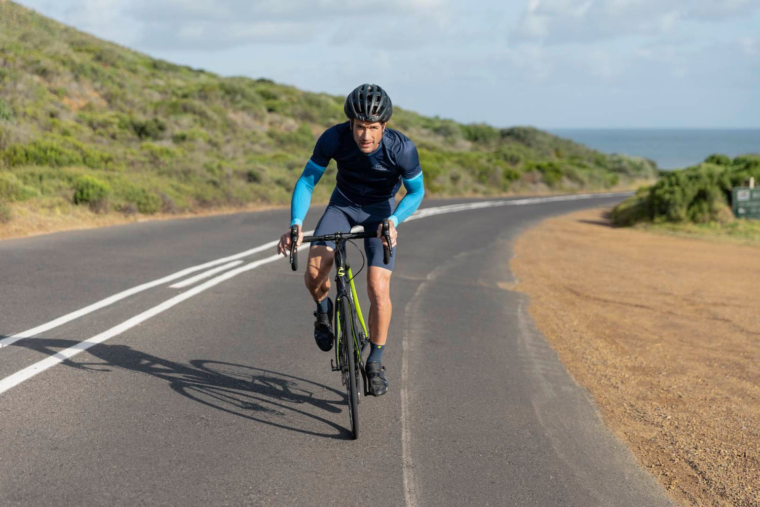 Man cycling for triathlon training. He is wearing Bauerfeind's compression arm sleeves to improve circulation and endurance