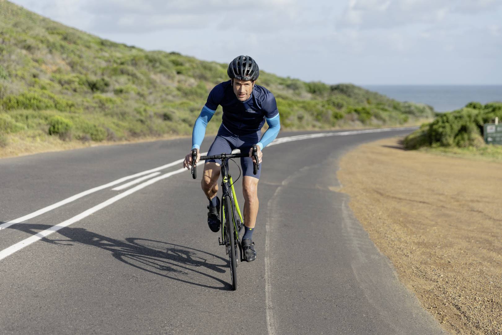 Man cycling for triathlon training. He is wearing Bauerfeind's compression arm sleeves to improve circulation and endurance