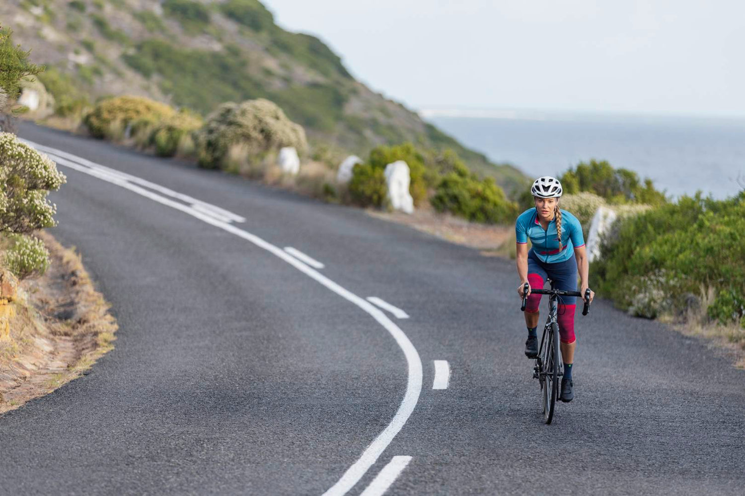 Woman cycling down a road in Bauerfeind Knee Compression Sleeves
