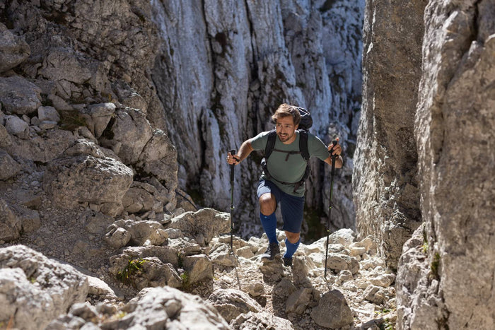 Man hiking up a steep mountain in sports performance socks