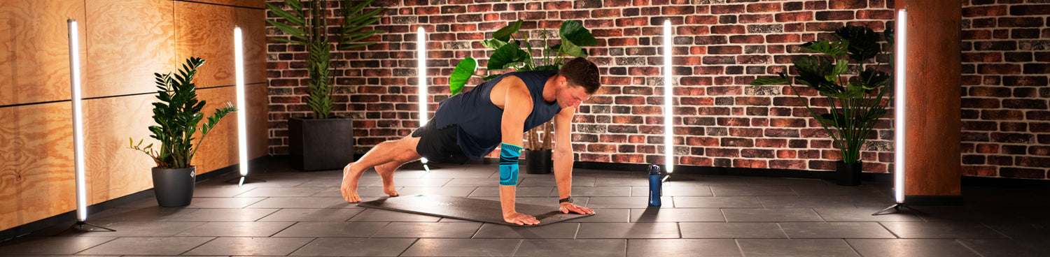 Thomas Roehler performing the plank taps workout for core and arm strength. He is wearing Bauerfeind's Sports Elbow Support