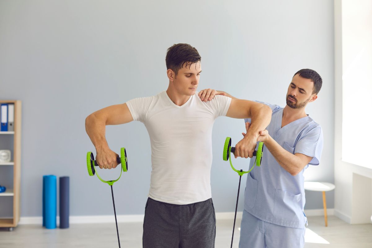 Man doing banded upright rows exercise with the assistance of a clinician