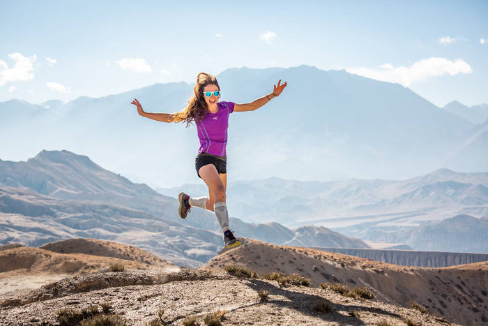 Woman running up a mountain trail in calf compression sleeves 