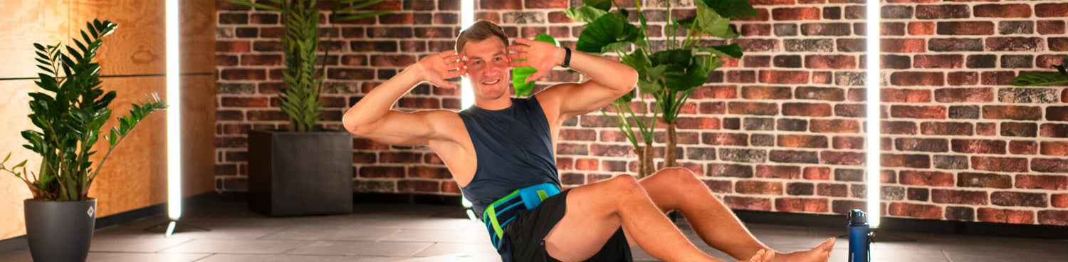 Thomas Roehler doing the Russian Twists workout for the core. He is wearing Bauerfeind's Sports Back Support