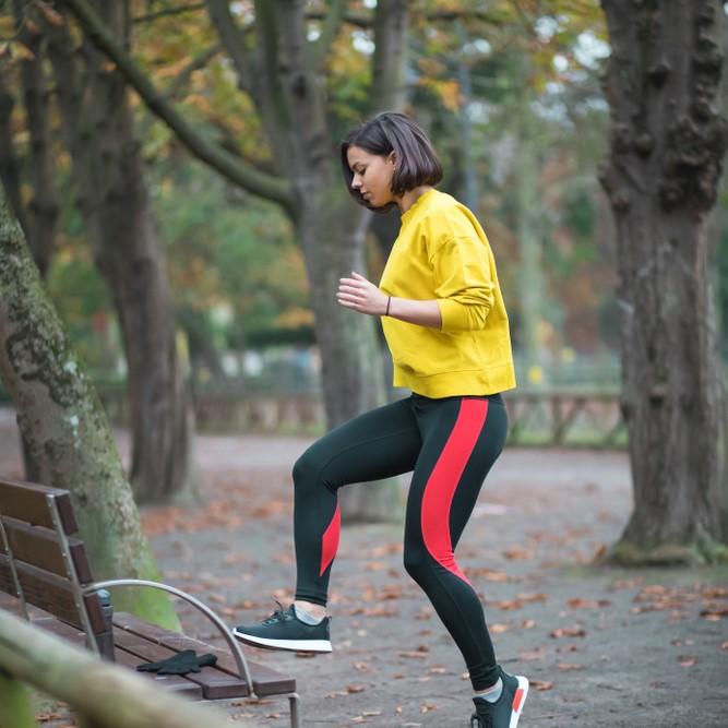 Woman doing the toe taps exercise in the woods using a fallen tree