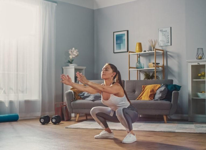 woman doing the sit to stand exercise in her living room to build leg and core strength