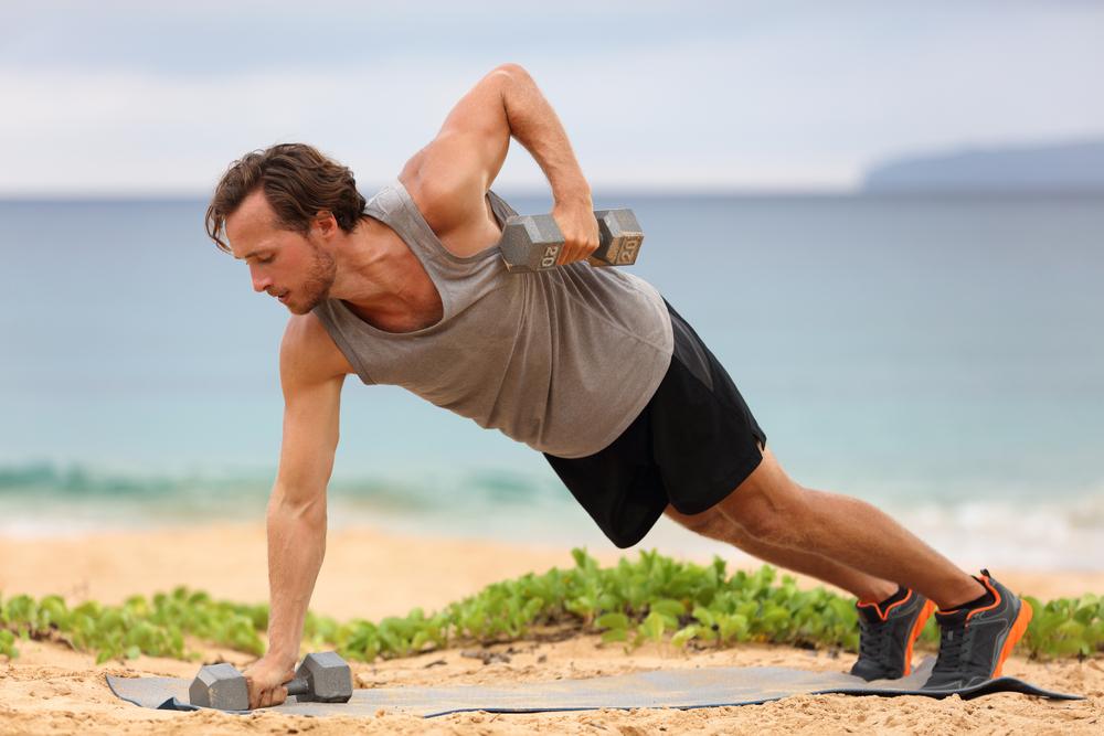 man at the beach performing the plank rows exercise for shoulder and core strength