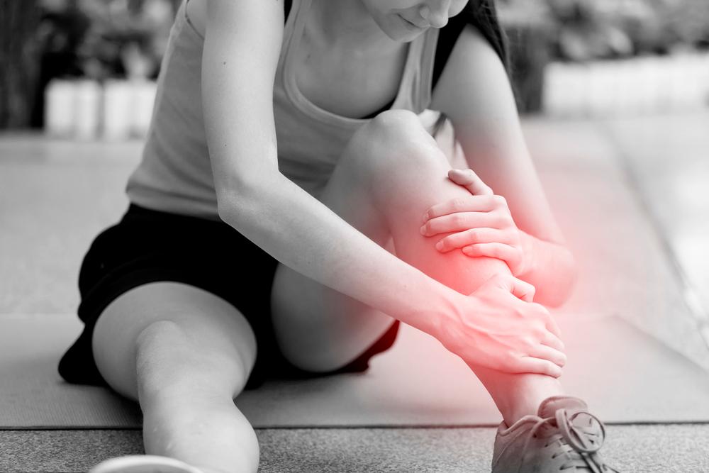 Person holding their shin in pain