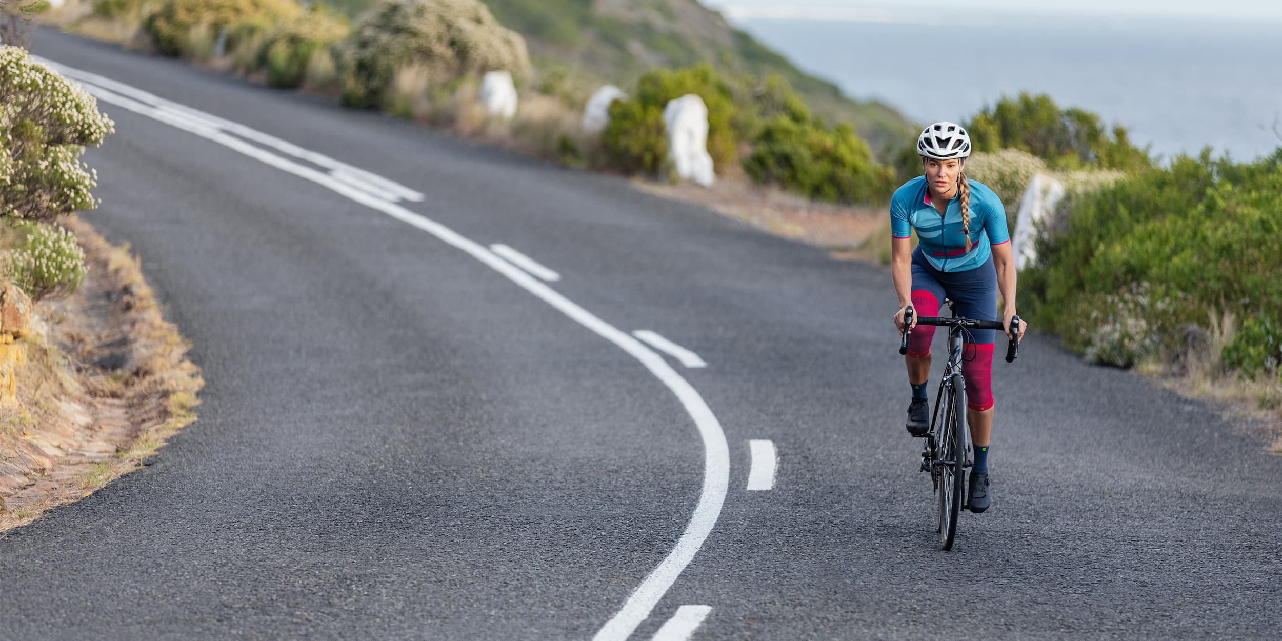 woman cycling along a road. She is wearing Bauerfeind's Compression Knee Supports