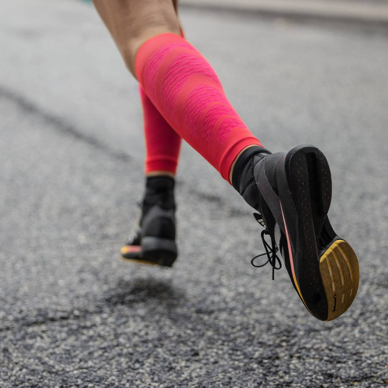 Person running on a road wearing pink socks and black running shoes.