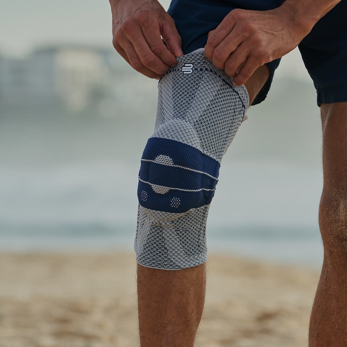 A man on the beach wearing a Bauerfeind GenuTrain knee support