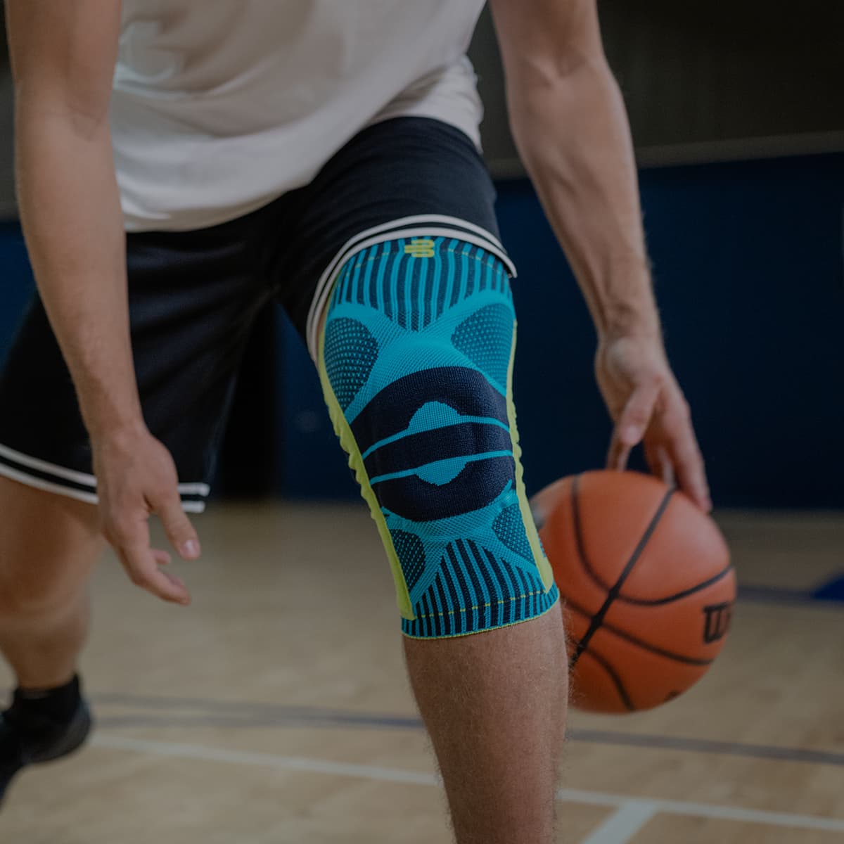 A man playing basketball wearing a Bauerfeind Sports Knee Support